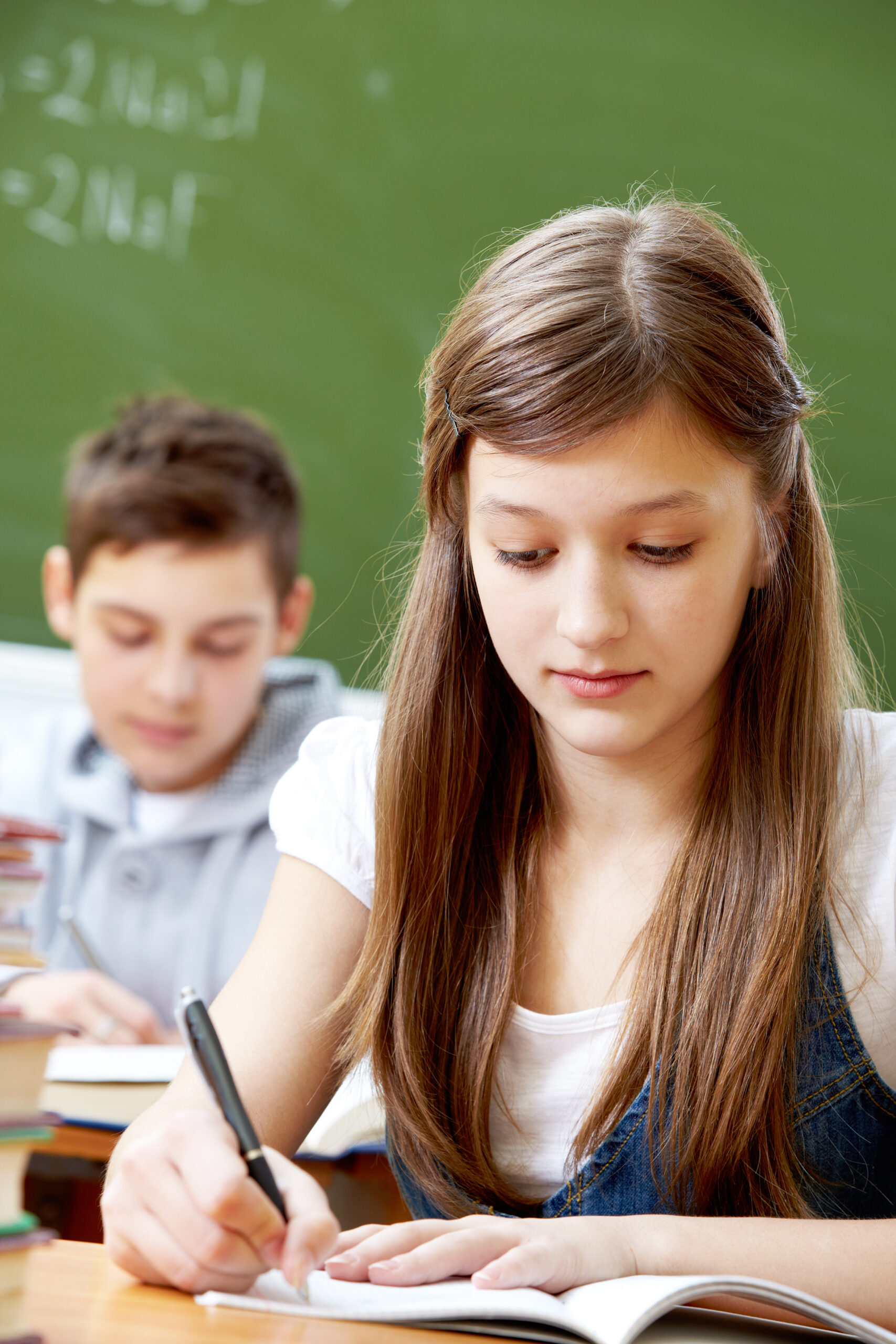 Adolescente concentrée en train d’écrire pendant un exercice scolaire en classe.